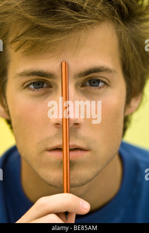 Jeune homme tenant un crayon jusqu'à front Banque D'Images