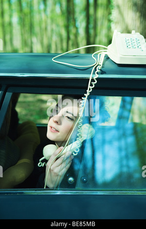 Jeune femme en parlant de voiture sur téléphone fixe Banque D'Images