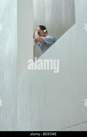 Man holding head, listening to headphones Banque D'Images