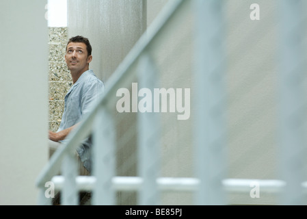 Homme assis sur les escaliers, looking up and smiling Banque D'Images