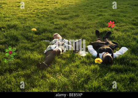 Deux femelles se trouvant dans les champs de fleurs, un ordinateur portable sur le terrain entre eux Banque D'Images