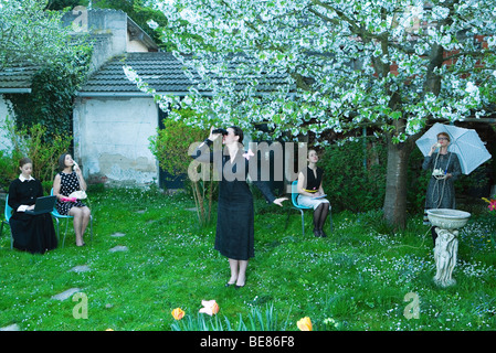 Femme regardant à travers des jumelles, papillon sur l'épaule, associés du bureau de travail en arrière-plan Banque D'Images