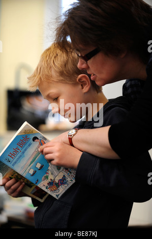 Un enseignant AIDE LES ENFANTS À UNE LECTURE DE LA BIBLE À UNE ÉCOLE DU DIMANCHE UK Banque D'Images