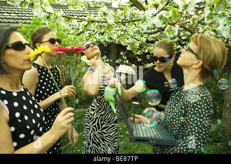 Groupe de femmes s'amuser en plein air, bubbles floating in foreground Banque D'Images