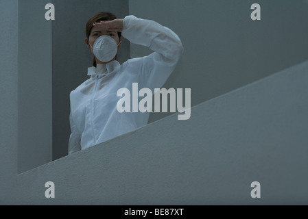 Femme en tenue de protection et masque de la pollution à l'écart, les yeux d'ombrage Banque D'Images