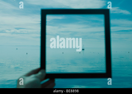 Personne holding picture frame en face de Seascape Banque D'Images