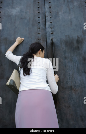 Femme frapper à porte, vue arrière Banque D'Images