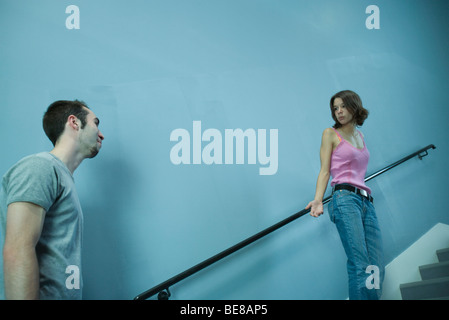 Femme qui monte pas, à l'homme derrière elle à l'air interrogateur Banque D'Images