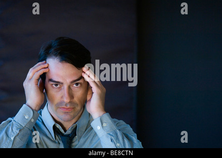 Businessman holding head, looking at camera Banque D'Images