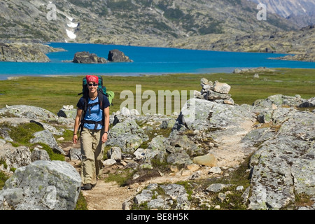 Jeune femme la randonnée, randonneur avec sac à dos, de la Piste-chilkoot historique, le col Chilkoot, lac de cratère derrière, la toundra alpine Banque D'Images