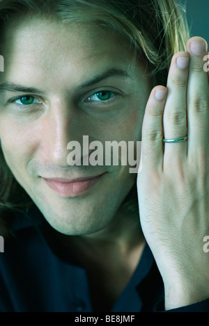 Man holding up part montrant anneau de mariage, smiling Banque D'Images