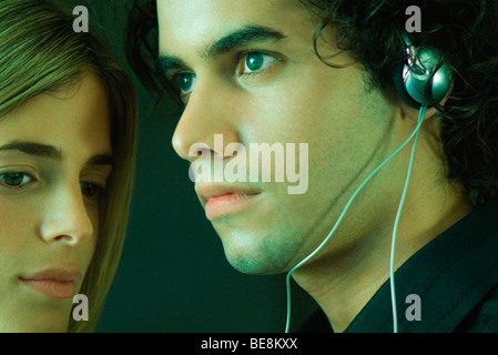 Jeune couple ensemble, man listening to headphones Banque D'Images