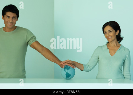 L'homme et de la femme avec les mains placées ensemble sur globe Banque D'Images