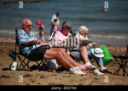 Trois vieilles gens assis sur la plage de sable de détente sur la plage Banque D'Images