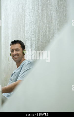 Man listening to headphones, smiling at camera Banque D'Images