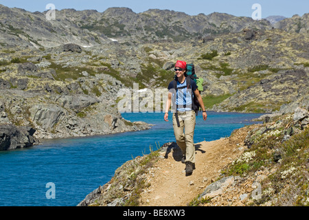 Jeune femme la randonnée, randonneur avec sac à dos, de la Piste-chilkoot historique, le col Chilkoot, lac de cratère derrière, la toundra alpine Banque D'Images