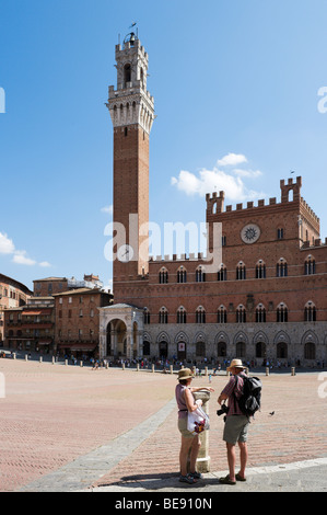 Couple d'âge moyen en face de la Torre del Mangia et le Palazzo Pubblico de Sienne, Il Campo, Toscane, Italie Banque D'Images