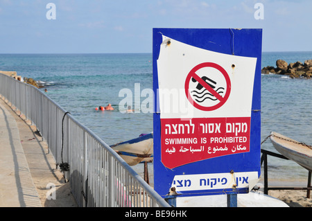 Israël, Haifa, Israël aller à la plage sur une journée chaude et ensoleillée. La natation de personnes à côté d'une piscine est interdit de signer Banque D'Images