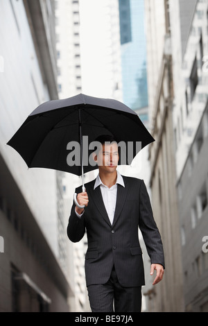 Businessman holding umbrella Banque D'Images