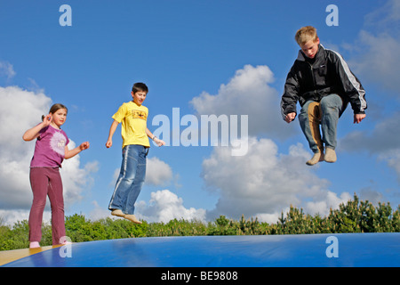 Trois enfants en train de sauter sur un château gonflable ensemble, Danemark Banque D'Images