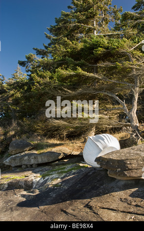 Petit bateau blanc renversé stockés le long de la côte de grès rocheux le long Berry Point Road, Gabriola Island, BC, Canada Banque D'Images