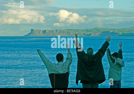 Une mère et ses deux fils mettre les bras debout sur Carrick-a-Rede Island, dans le comté d'Antrim, en Irlande du Nord Banque D'Images