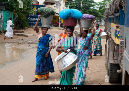 Les femmes indiennes transportant lavage des vêtements dans des seaux sur la tête il y a à travers le village de Puttaparthi, Andhra Pradesh, Inde Banque D'Images