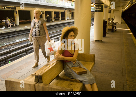 Jeune femme attend un Q train à l'église de métro Avenue à Brooklyn, New York Banque D'Images