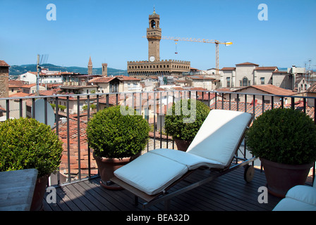 Soleil chaise longue sur le balcon de la suite penthouse de l'hôtel Continentale avec une vue sur le Palazzo Vecchio à Florence Banque D'Images