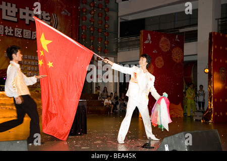 Journée nationale en Chine, Shenzhen. 60e anniversaire de fondation de la Chine. Jeune Magicien en spectacle avec drapeau chinois. Banque D'Images