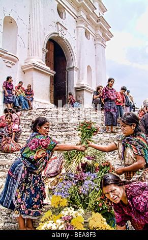 Femme en tissus imprimés colorés vendant des fleurs colorées sur les étapes de l'ancienne cathédrale à Chichicastenango Guatemala sur le marché Banque D'Images