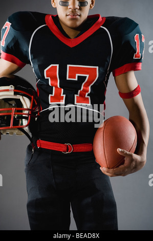 Mixed Race football player holding football Banque D'Images