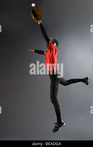 Mixed Race baseball player catching ball Banque D'Images