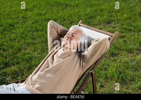 A senior man repose dans une chaise longue sur la pelouse Banque D'Images