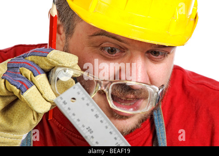 Young caucasian handyman vérifier misure sur son instrument Banque D'Images