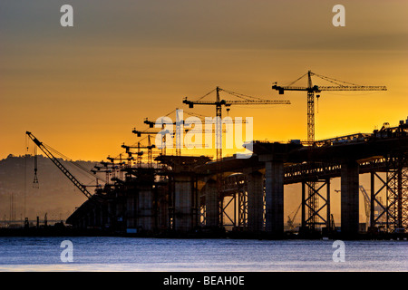 S'élever au-dessus de grues le nouveau l'Est de l'envergure de la Bay Bridge se lève tôt matin léger comme vu de l'île au trésor Banque D'Images