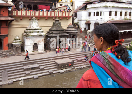 Femme népalaise en sari aux couleurs vives donnant sur la rivière Bagmati au temple de Pashupatinath, Katmandou, Népal Banque D'Images