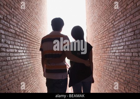 Asian couple marcher entre des murs de brique Banque D'Images