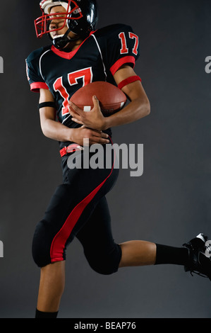 Mixed Race football player holding football Banque D'Images