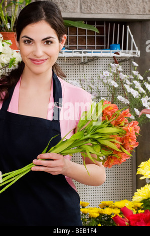 Femme tenant un bouquet de fleurs et souriant Banque D'Images