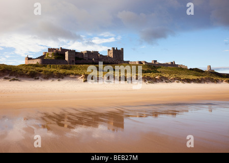 Château de Bamburgh reflétée dans le sable humide sur une plage de sable vide de l'estran. , Bamburgh Northumberland, England, UK, Grande-Bretagne Banque D'Images