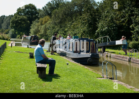 Homme assis sur banc rustique sanglier étroite observation 68 Verrouillage sur Kennet and Avon Canal Banque D'Images