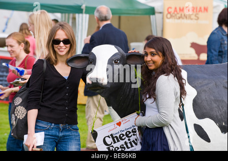 Deux jeunes femmes se faire prendre en photo avec la Vache en plastique promotionnel au Great British Cheese Festival Cardiff South Wales UK Banque D'Images