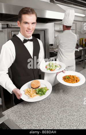 Les plaques d'aliments Waiter holding Banque D'Images