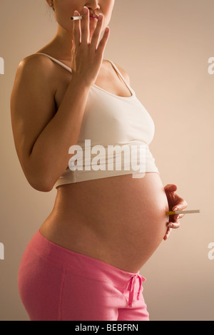 Femme enceinte fume une cigarette Banque D'Images