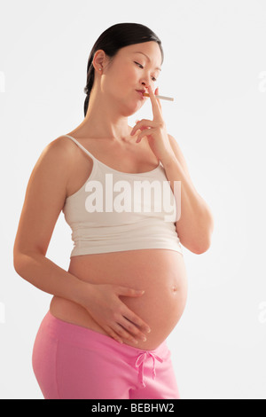 Femme enceinte fume une cigarette Banque D'Images