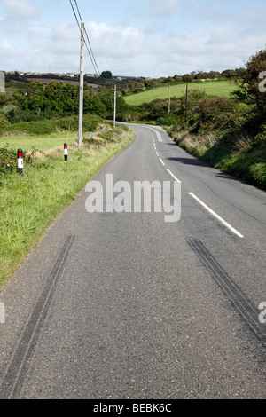 Marques de dérapage des pneus sur une route de campagne à Cornwall, UK. Banque D'Images