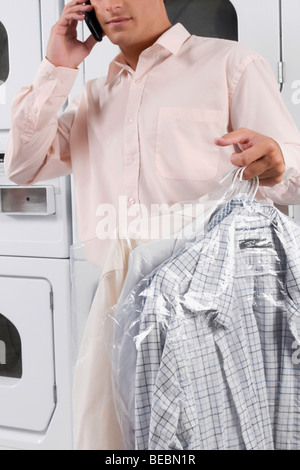 Man talking on a mobile phone et holding shirts Banque D'Images