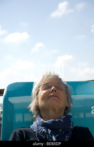 Femme d'âge mûr assise sur un transat au bord de la mer Banque D'Images