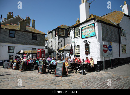 Les gens boire et manger à l'extérieur du Sloop Inn pub sur le front de mer à St Ives, Cornwall, Angleterre Banque D'Images